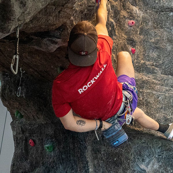 A student reaching for a handhold on The Ridge rock wall.